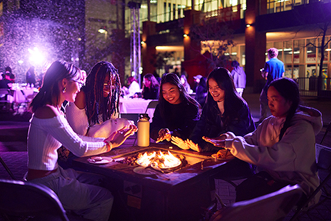 Students sit around a fire pit