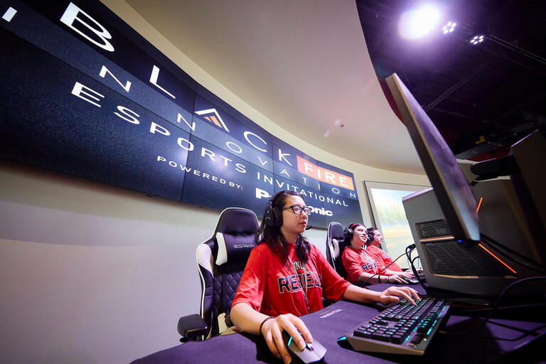three people in front of gaming computers