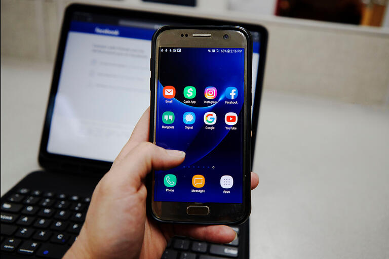 hand holding cell phone with social media apps on screen