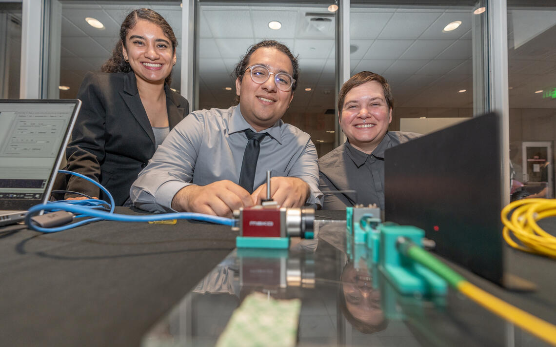 Three UNLV Engineering students gather around their innovation during the May 2023 Senior Design competition