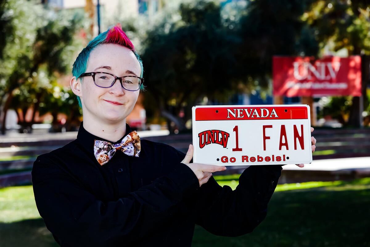 Alum holds up license plate