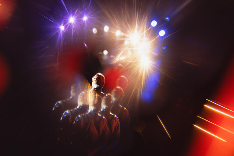 man on stage surrounded by lights in a kaleidoscope effect