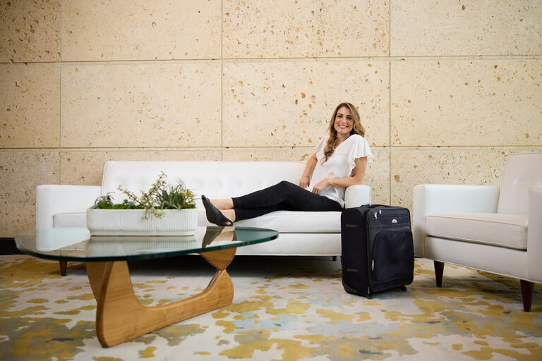woman lying on couch next to piece of luggage