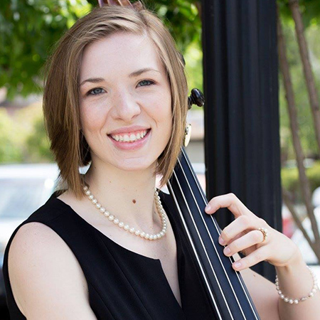 A woman smiling with a cello in her hand