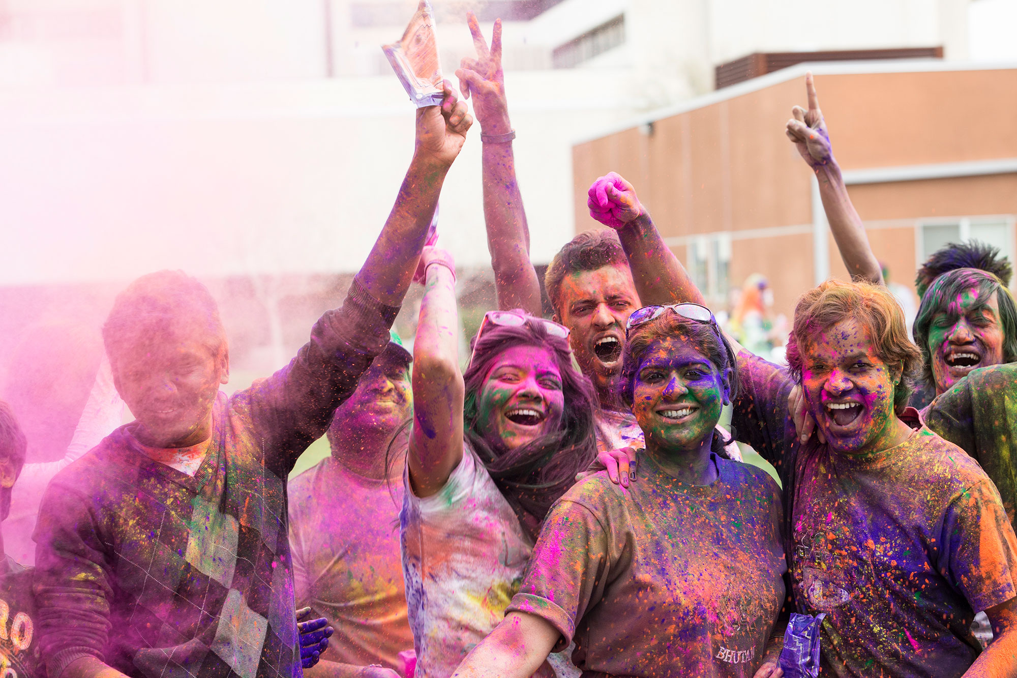 Group of students smiling through a cloud of pink powdered color