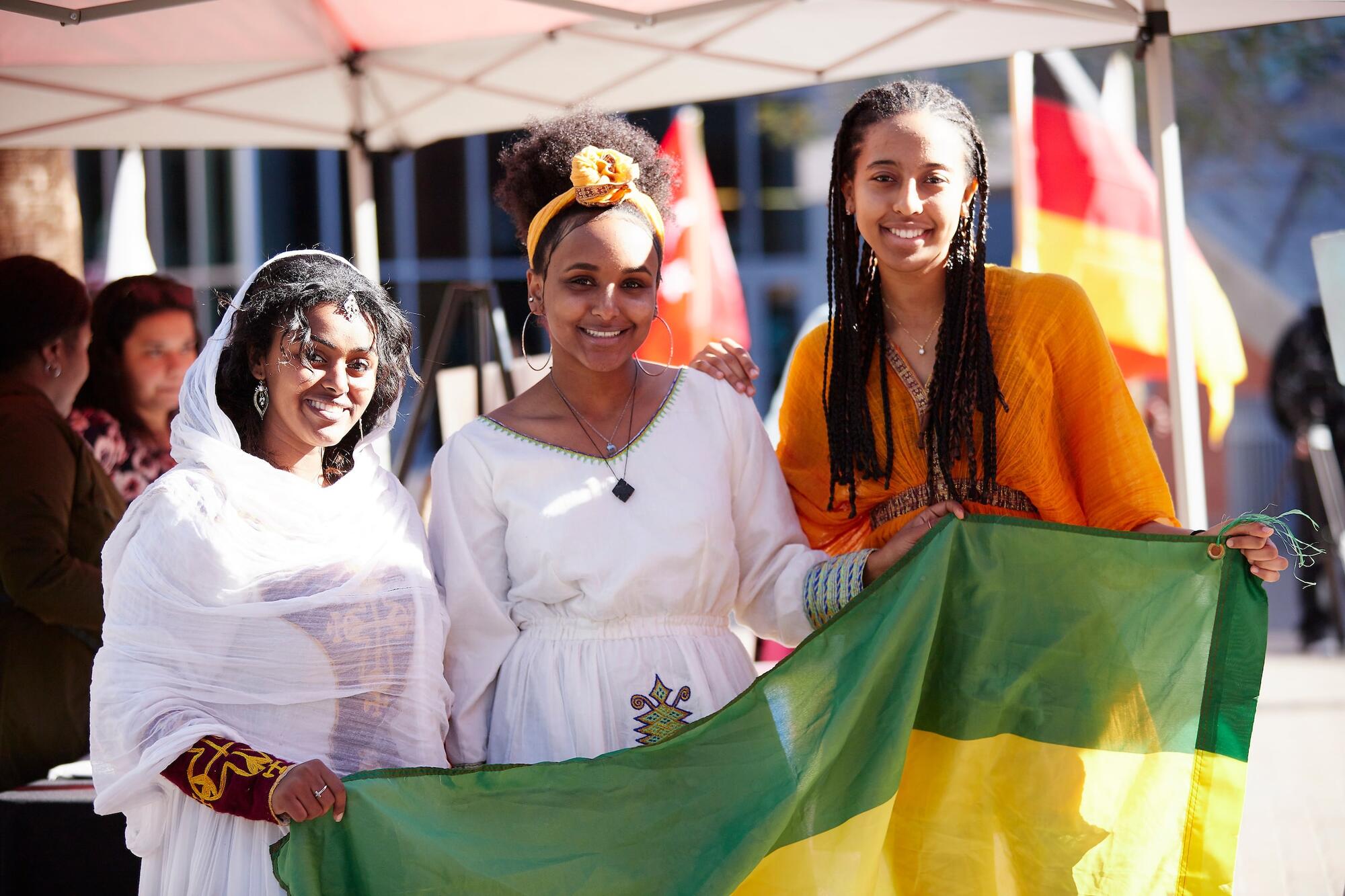 Three people smiling with a flag.