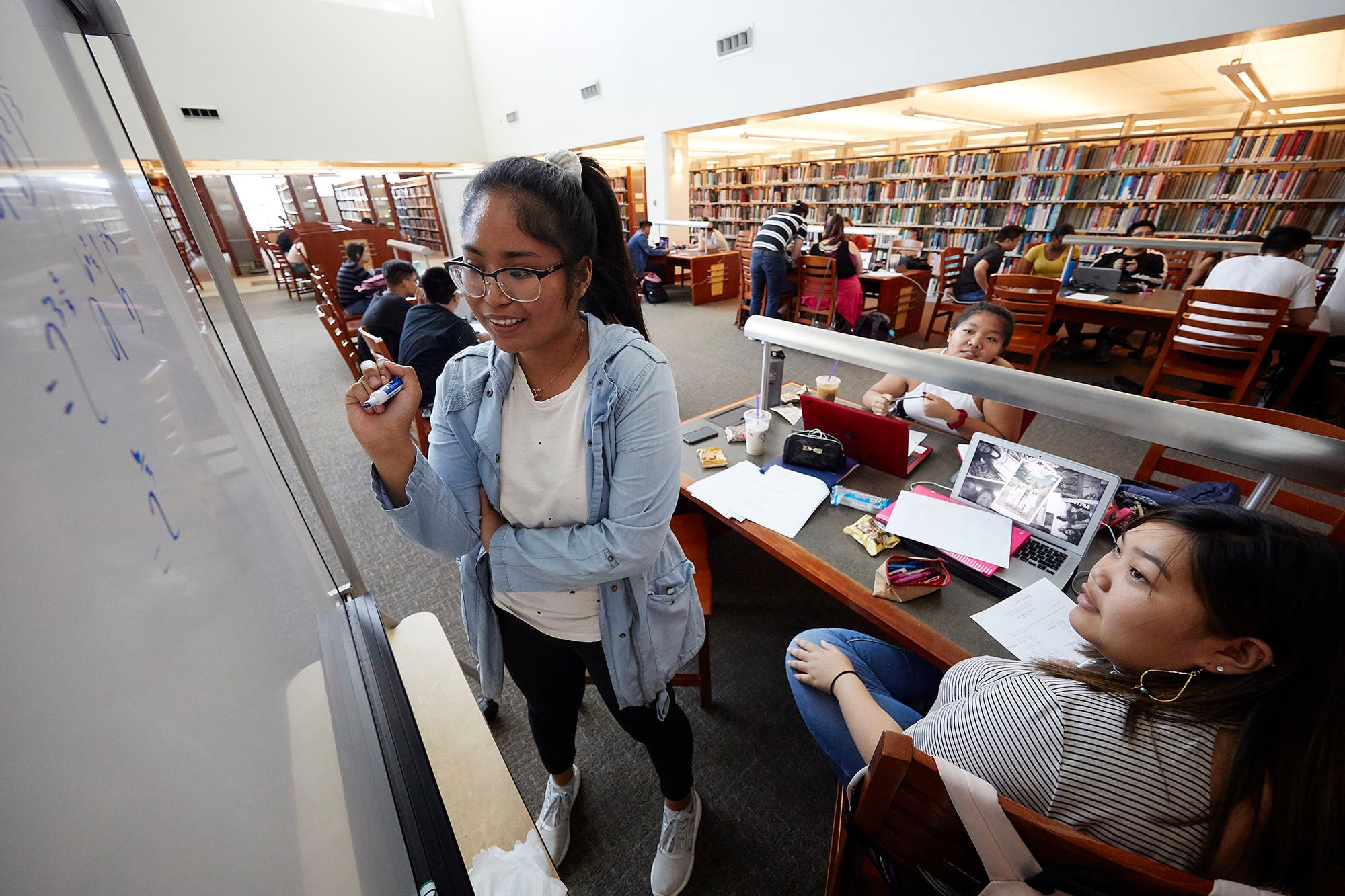 Students in the library working on equations a white board.