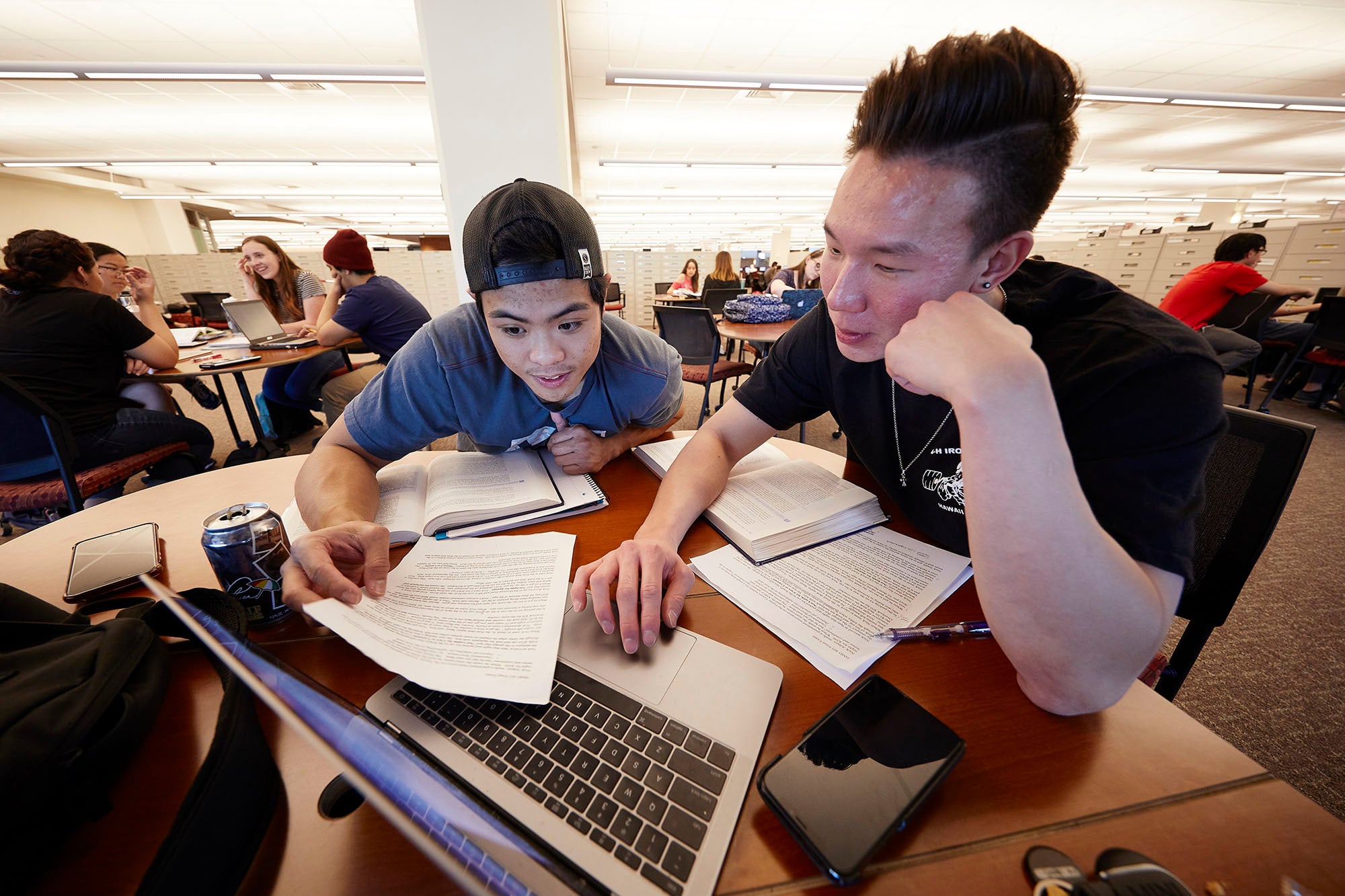 Students in the library working together on a laptop.