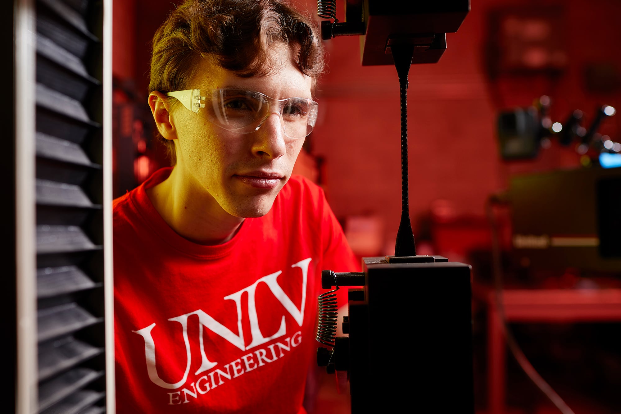 A man wearing safety goggles working on an engineer project.