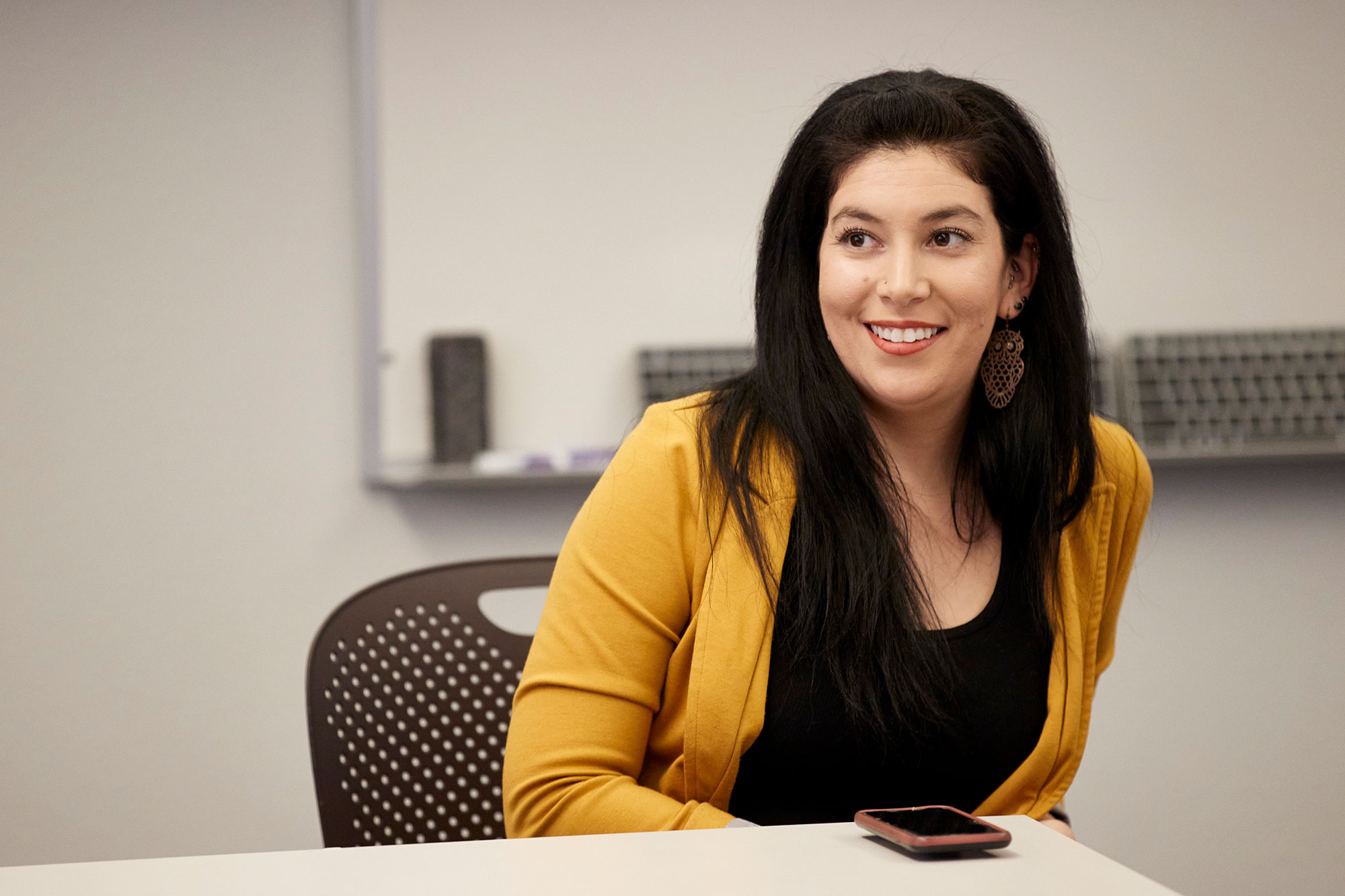 A woman wearing a yellow blazer and a black blouse.