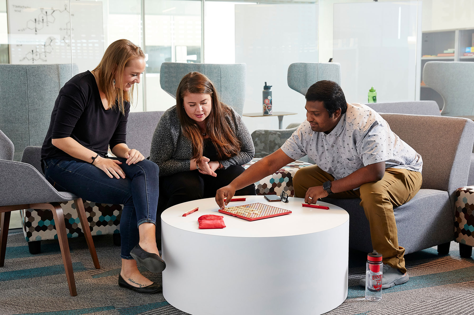 Three people sitting together looking down at a board on a table