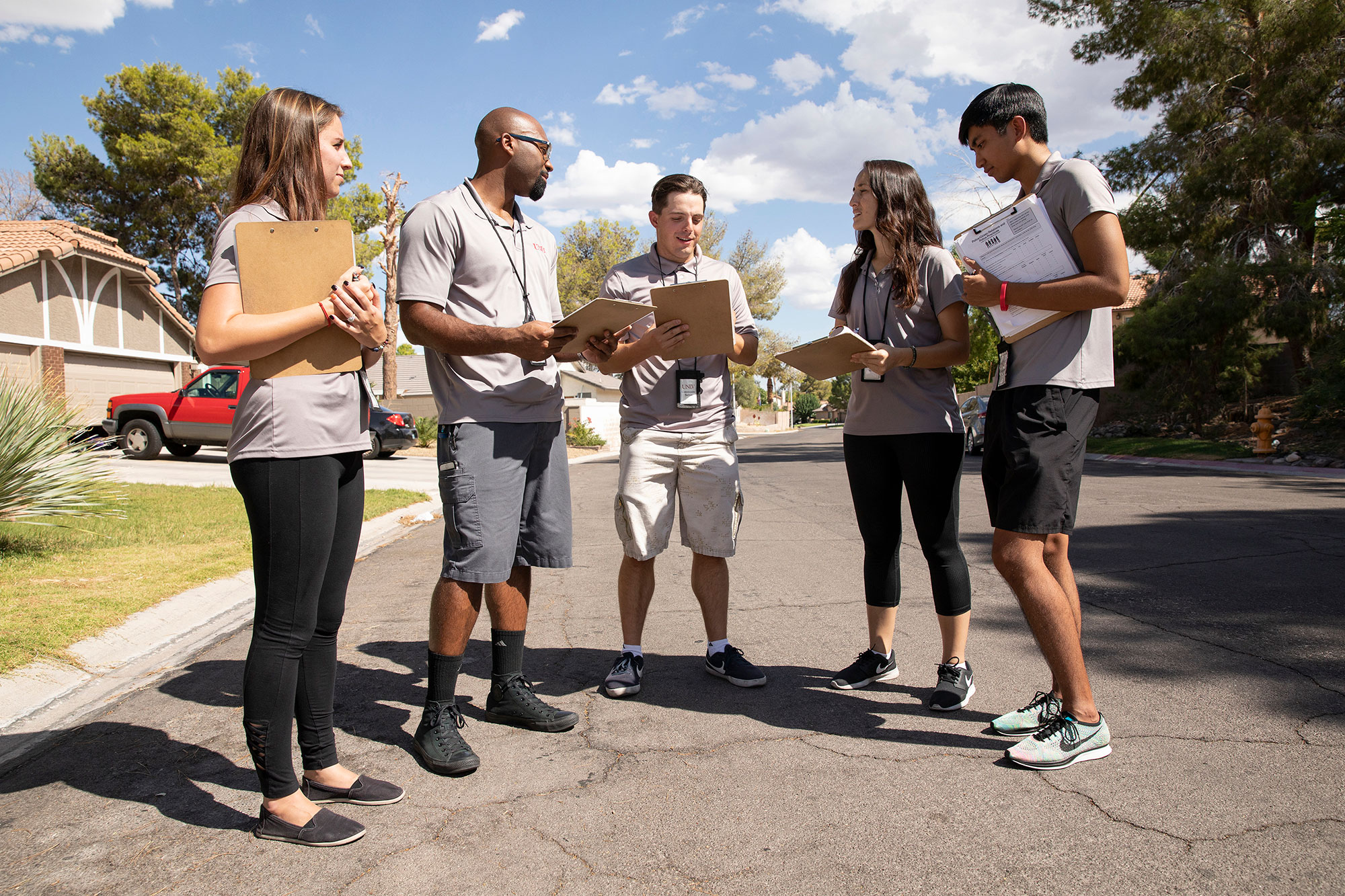 A group of five people with clipboards having a conversation