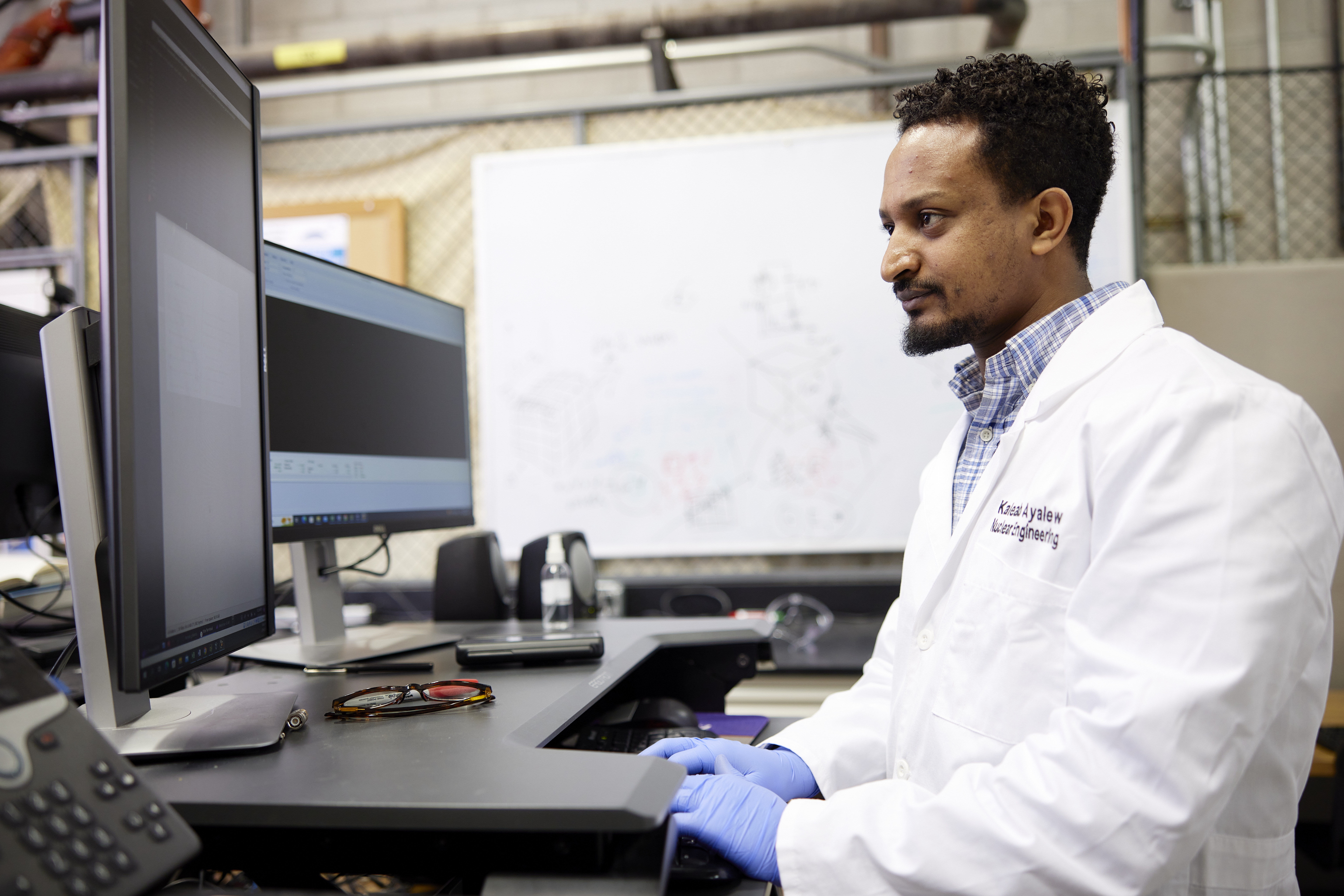 person wearing a lab coat and looking at a computer