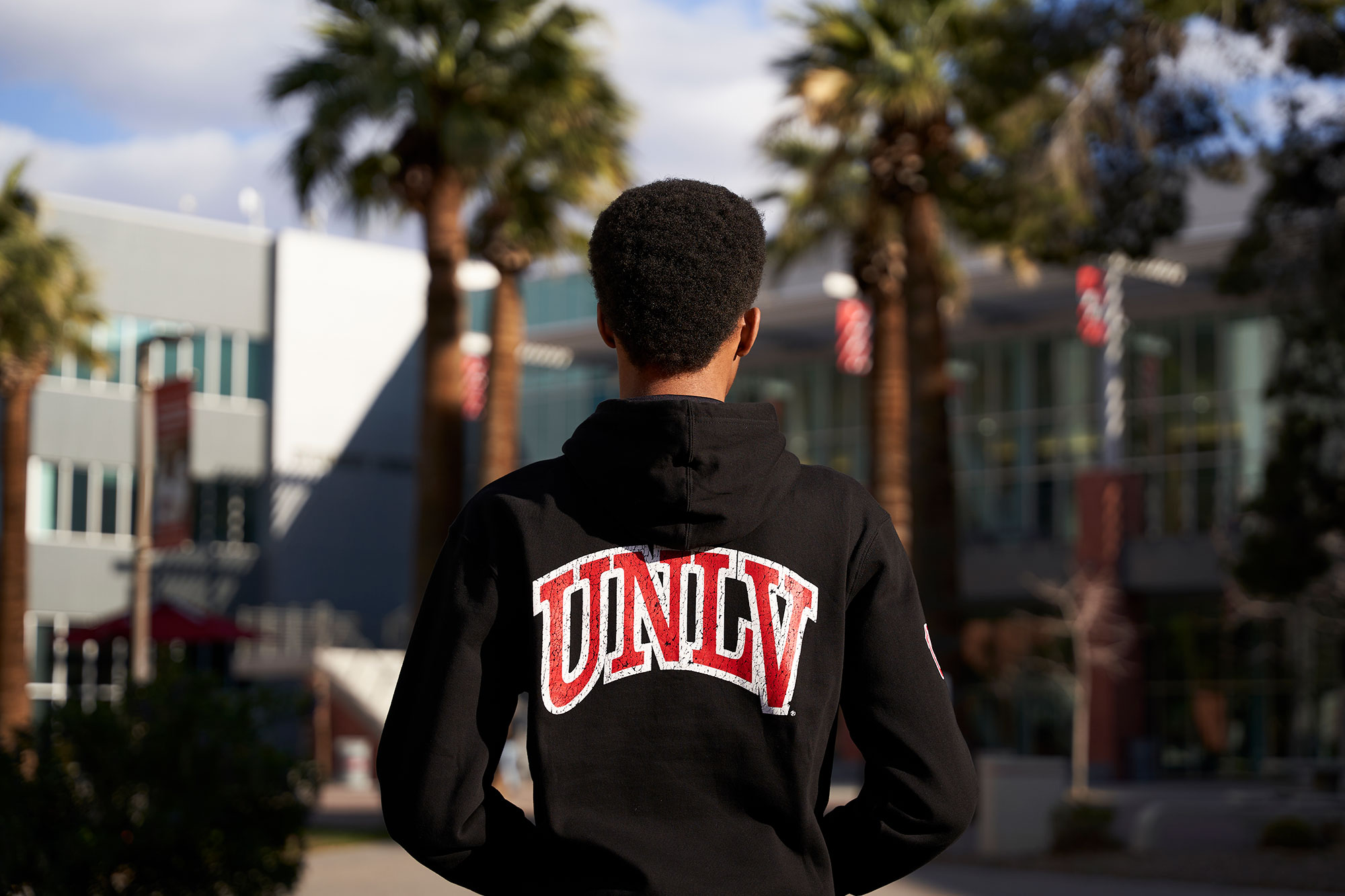 A student wearing an U-N-L-V sweatshirt standing in front of the Student Union