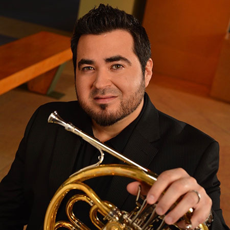 Headshot of Chris Castellanos holding a French Horn