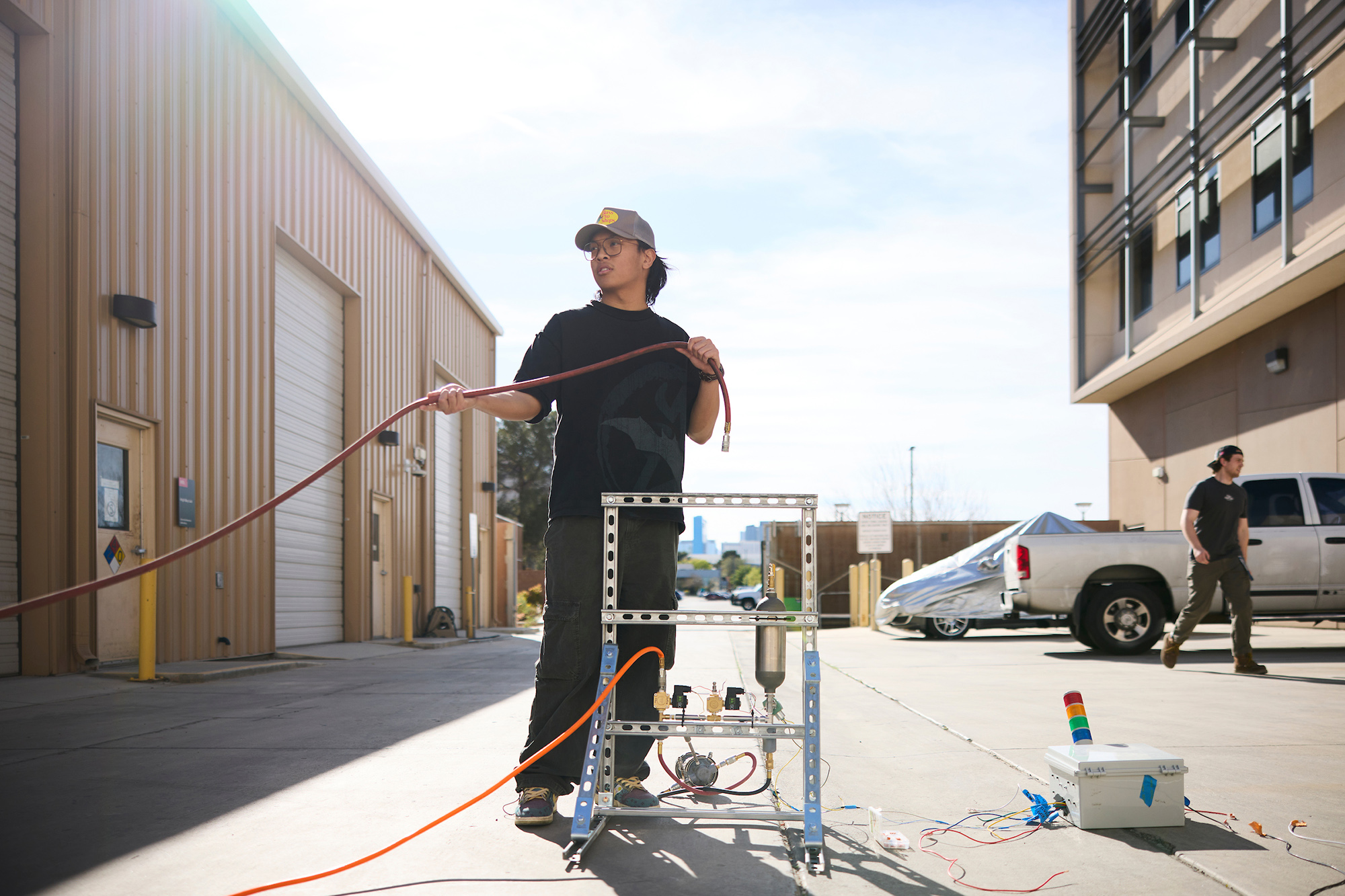 Young man standing behind a mechanical rig pulling on a hose