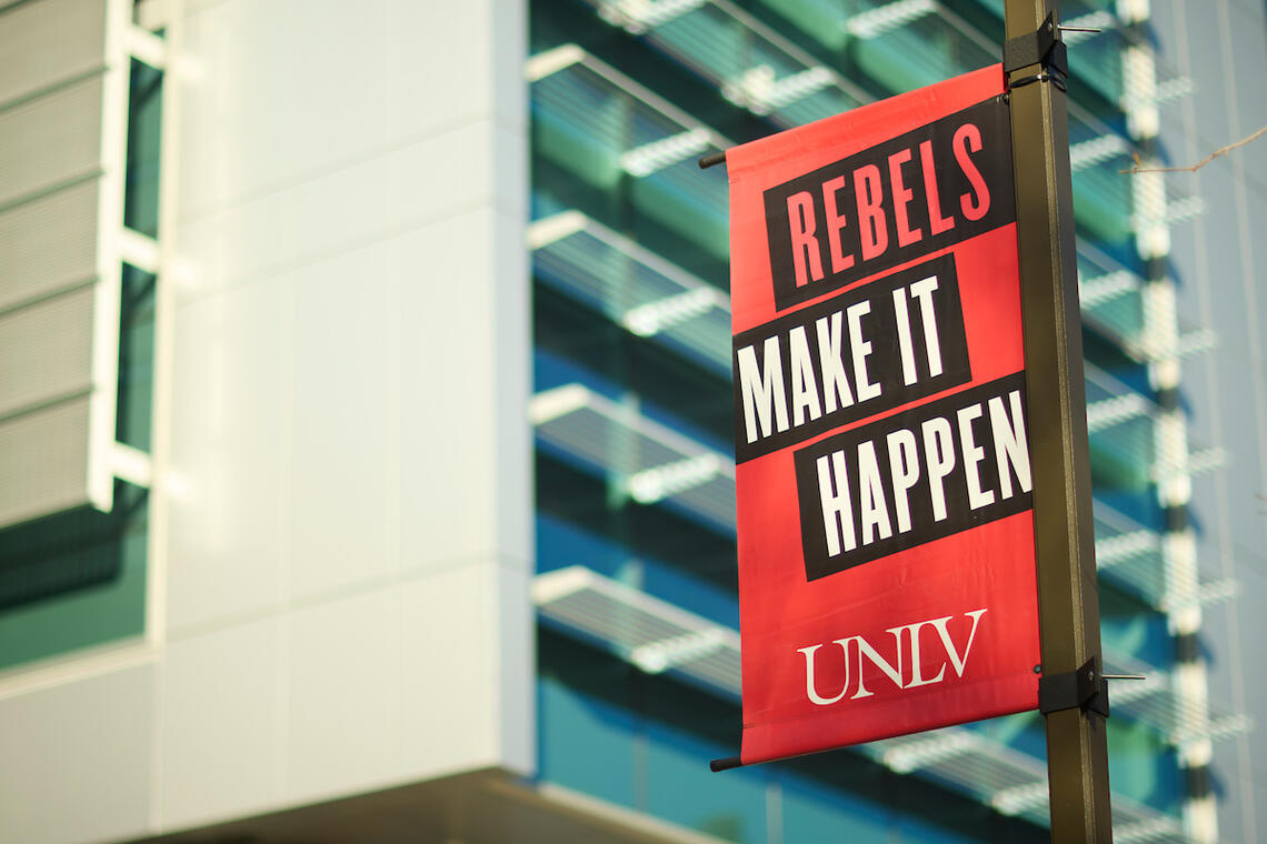 A closeup image of a Rebels Make it Happen sign in front of the Advanced Engineering Building