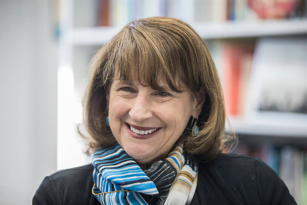 woman with short hair and blue shall smiling into the camera