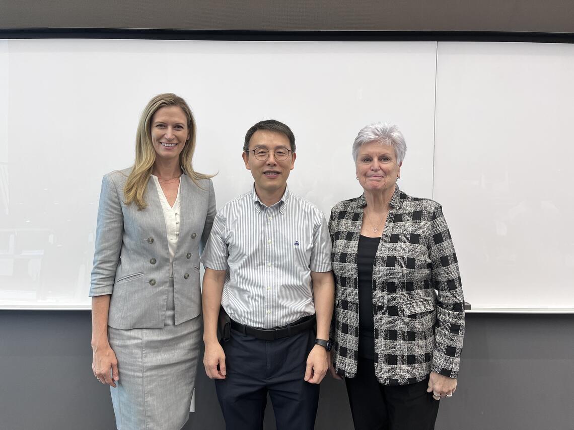 Three people pose for a photo in front of a whiteboard