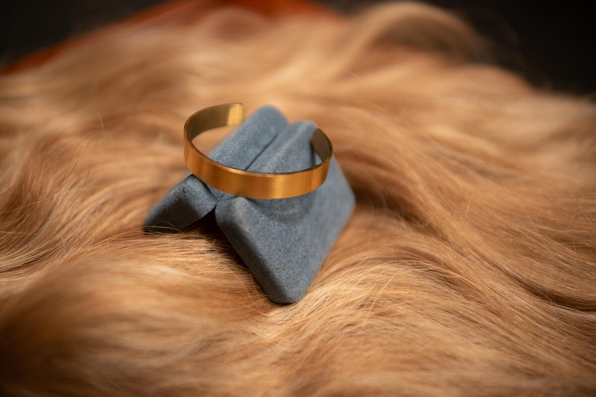 A gold ring sitting on top of a blue open box and yellow hair