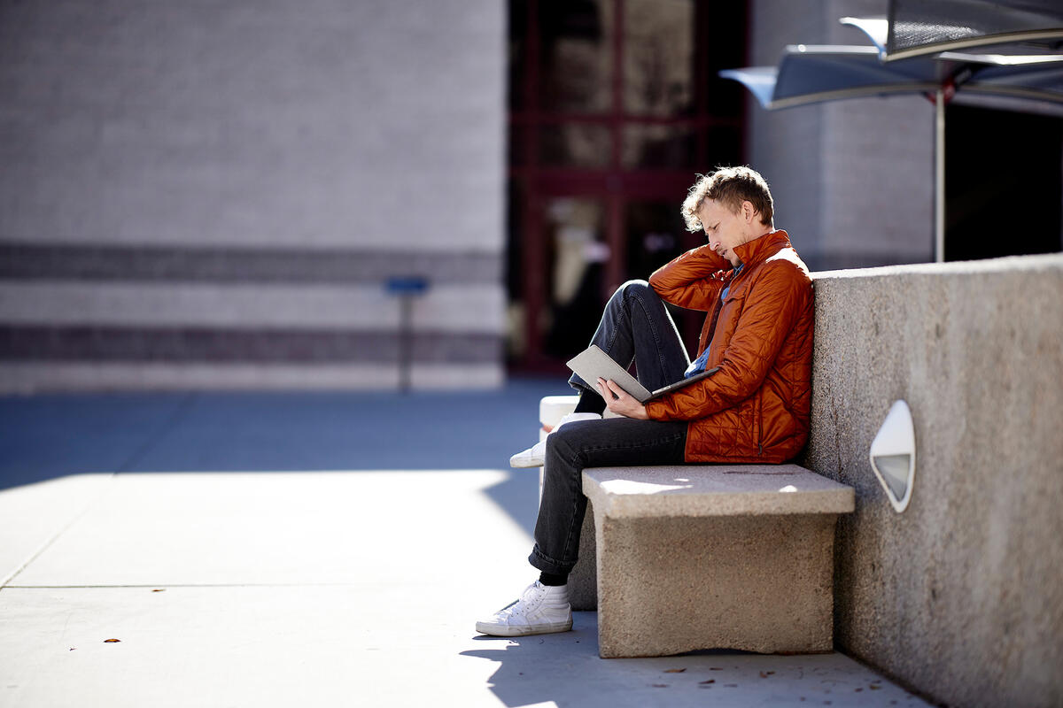 person reading a book on a bench