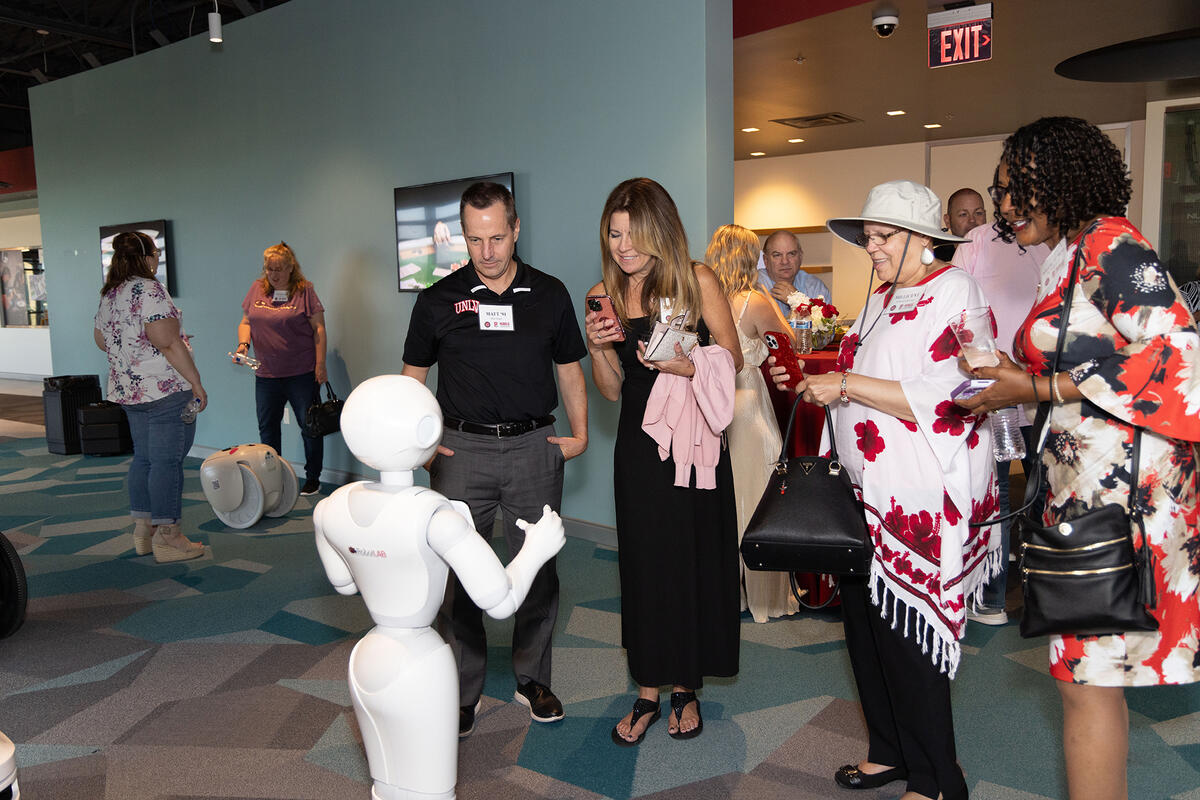 Group of people circled around a white human-like robot