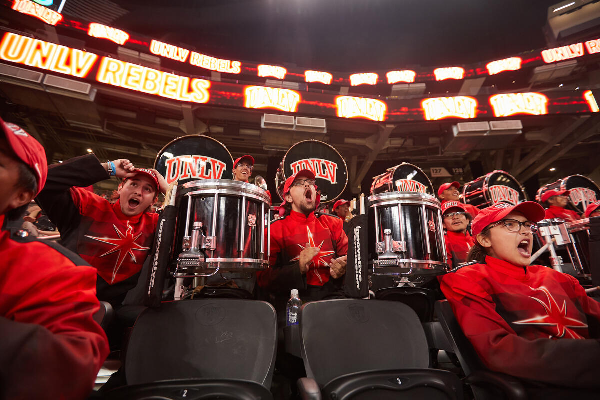 A band holding drums wearing red uniforms