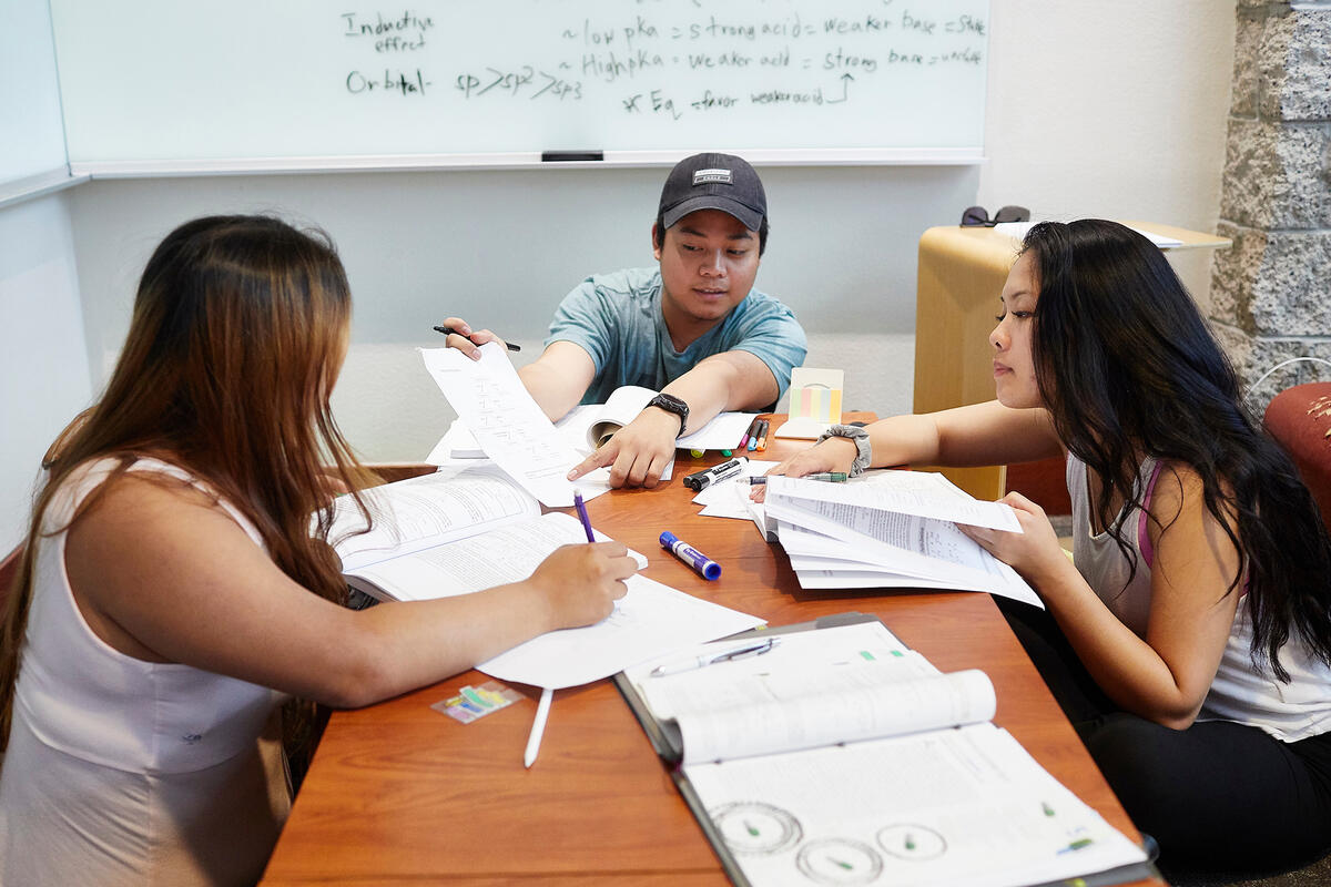 Three people studying on a desk