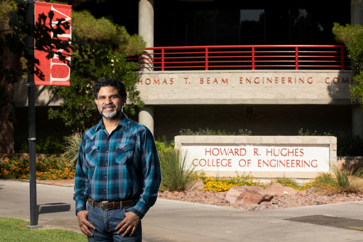 man in flannel shirt stands in front of UNLV engineering building