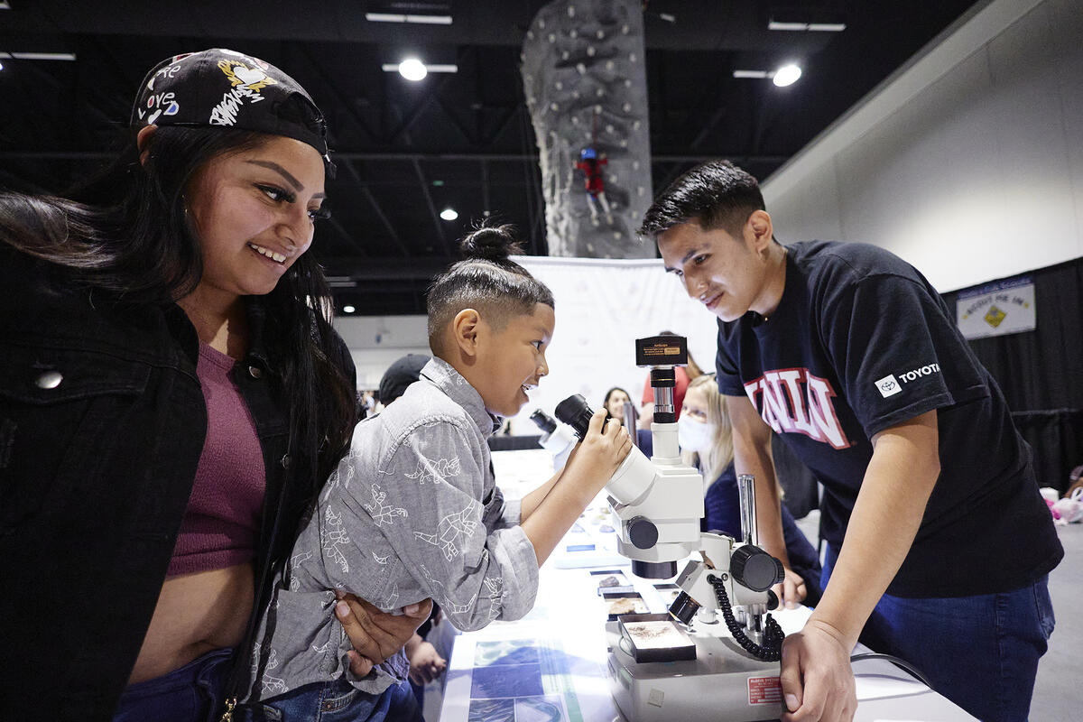 a person carrying a child to see through a microscope