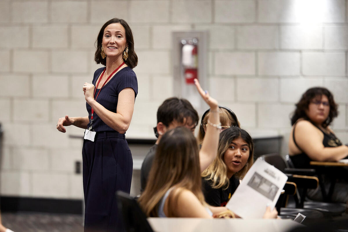 An instructor speaking to a group of students in a lecture hall.