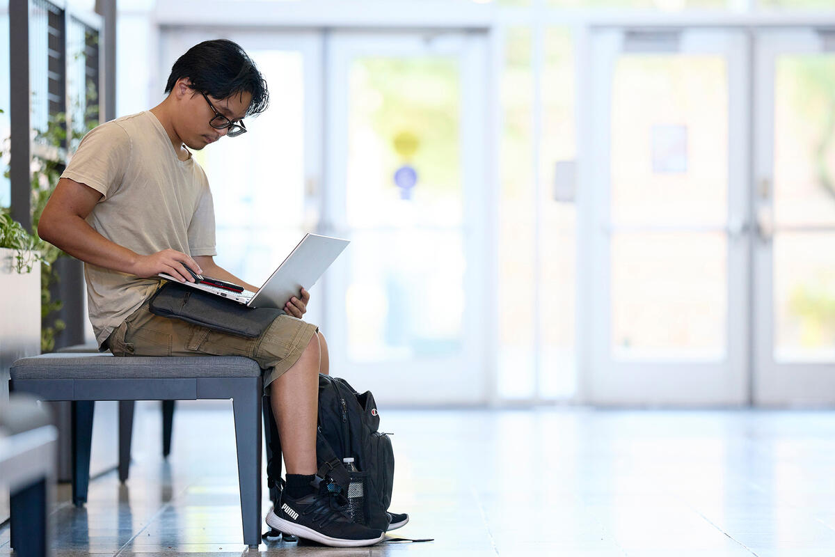 a person sitting on a bench with a laptop