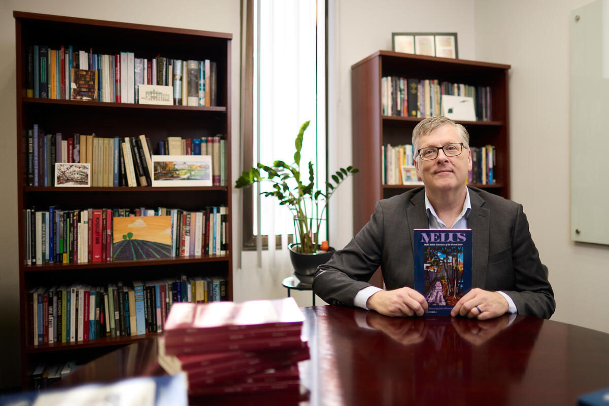 man sat at desk in office holding a book