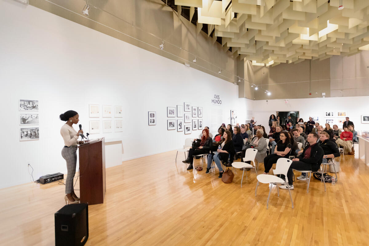 A woman speaks to an audience in the Marjorie Barrick Museum of Art