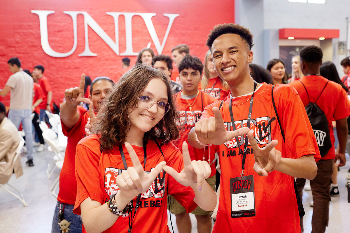 Two students at orientation making L-V using their hands