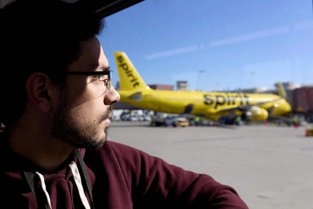 A student looks over an airport tarmac; a plane is in the background.