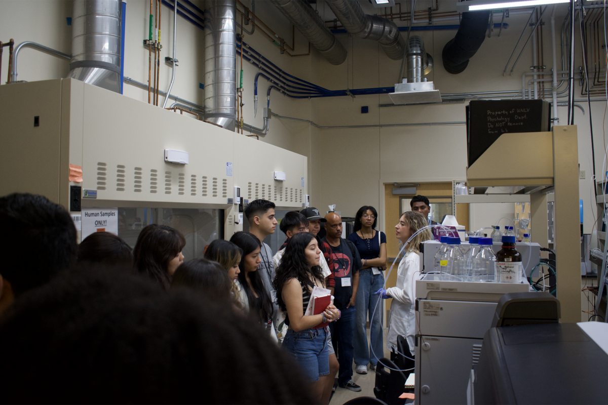 Group of people on a tour in a chemistry lab with main speaker in lab coat.
