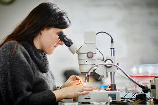 A woman looking into a microscope.