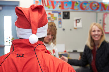 Shot of UNLV employee wearing Santa cap engaging with staff.