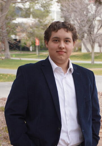 young student poses in suit jacket and button up shirt