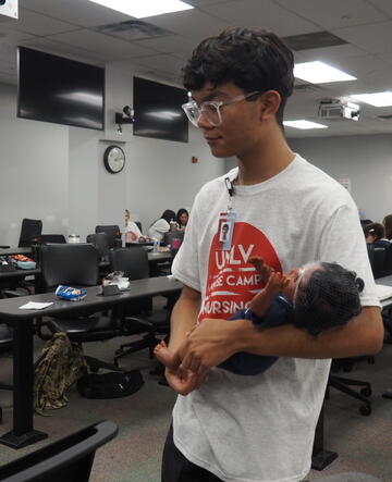 student holding infant-sized manikin at nurse camp