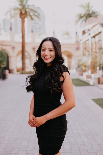 Darlyn Magaña, wearing black dress, smiles at camera