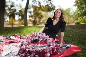 woman sits on quilt made of shirts with wreath in her lap