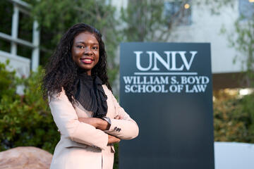 woman with crossed arms stands in front of Boyd School of Law sign