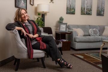 Gretchen Grierson sits on a gray chair in her office