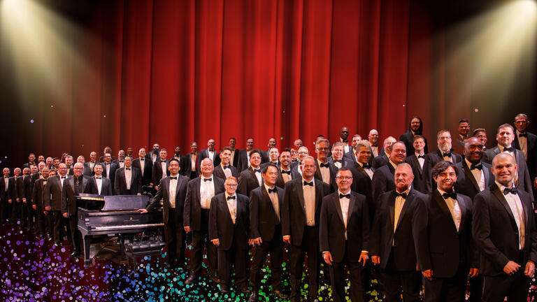 An image of the members of the Las Vegas Men's Chorus superimposed over an image of a stage with a closed red curtain.