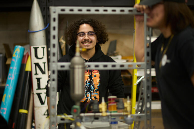 A student working in a workshop, with a rocket labeled &quot;UNLV&quot;