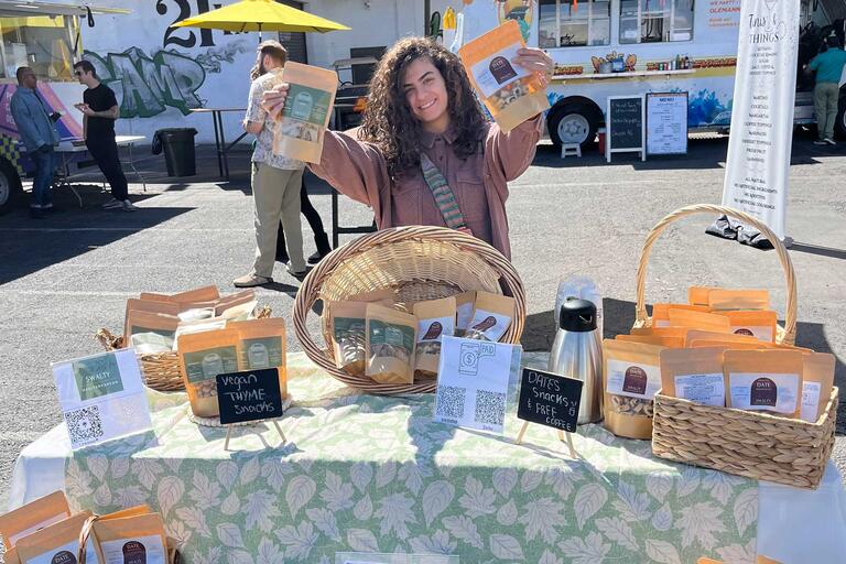 student displays vegan product on table during market