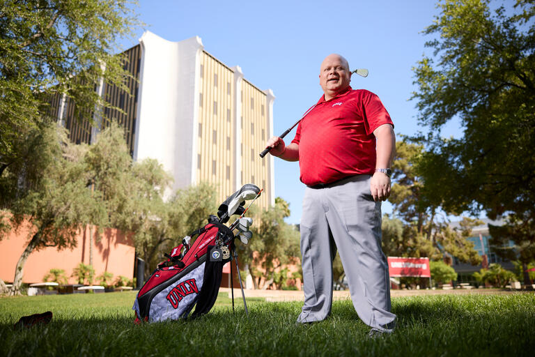 man in red shirt holding golf club