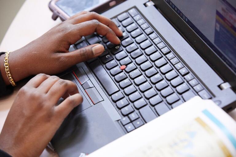 A person typing on a computer laptop.